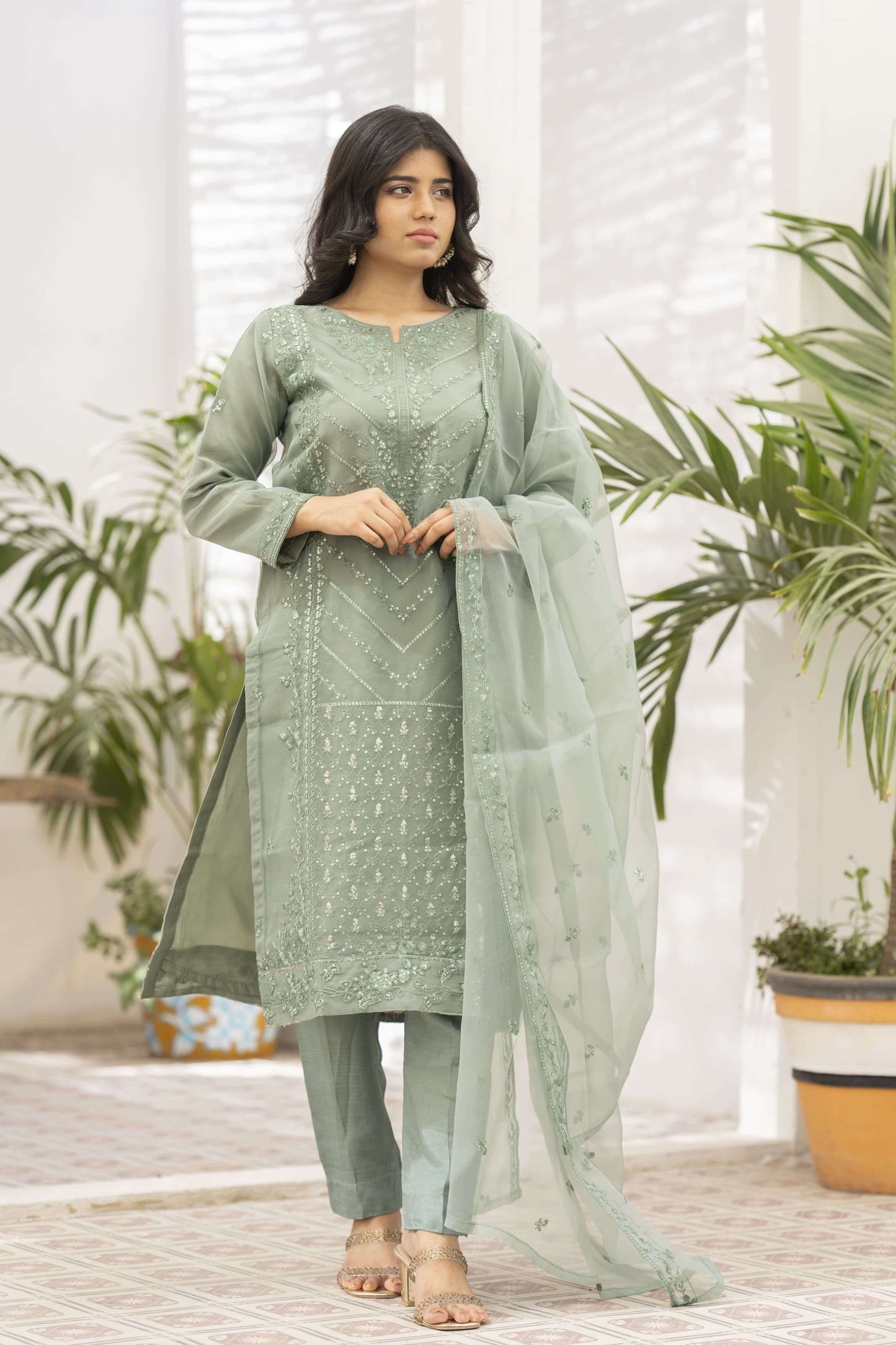 Woman wearing a light green traditional outfit with dupatta on shoulder