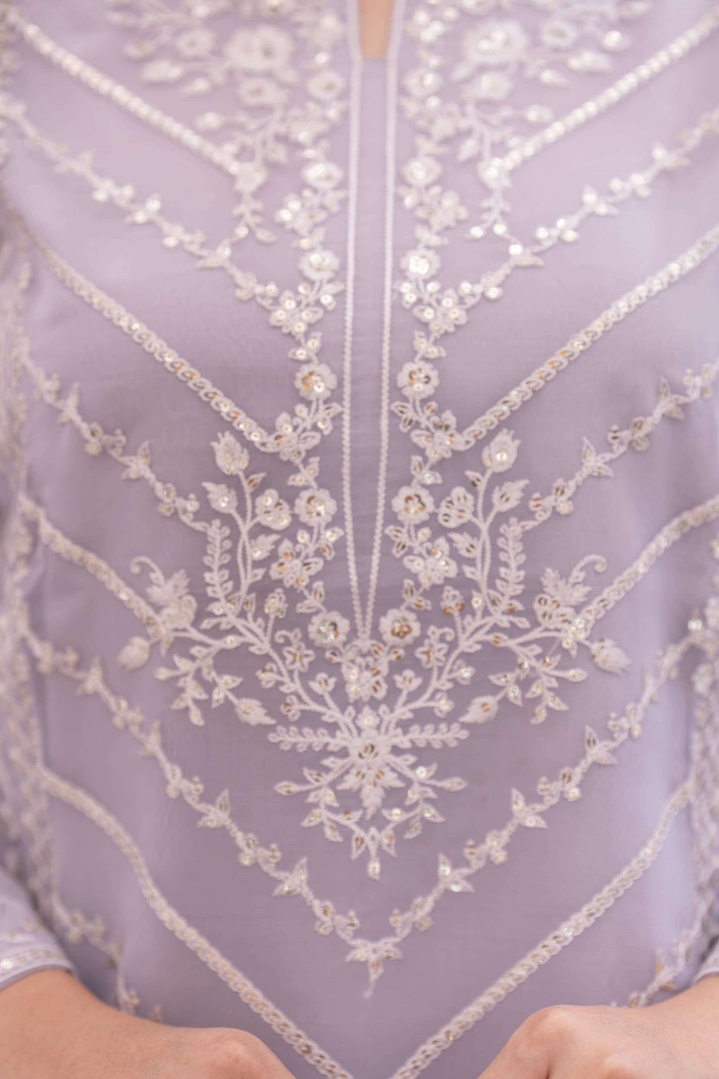 Close-up of a lavender garment with intricate white floral embroidery
