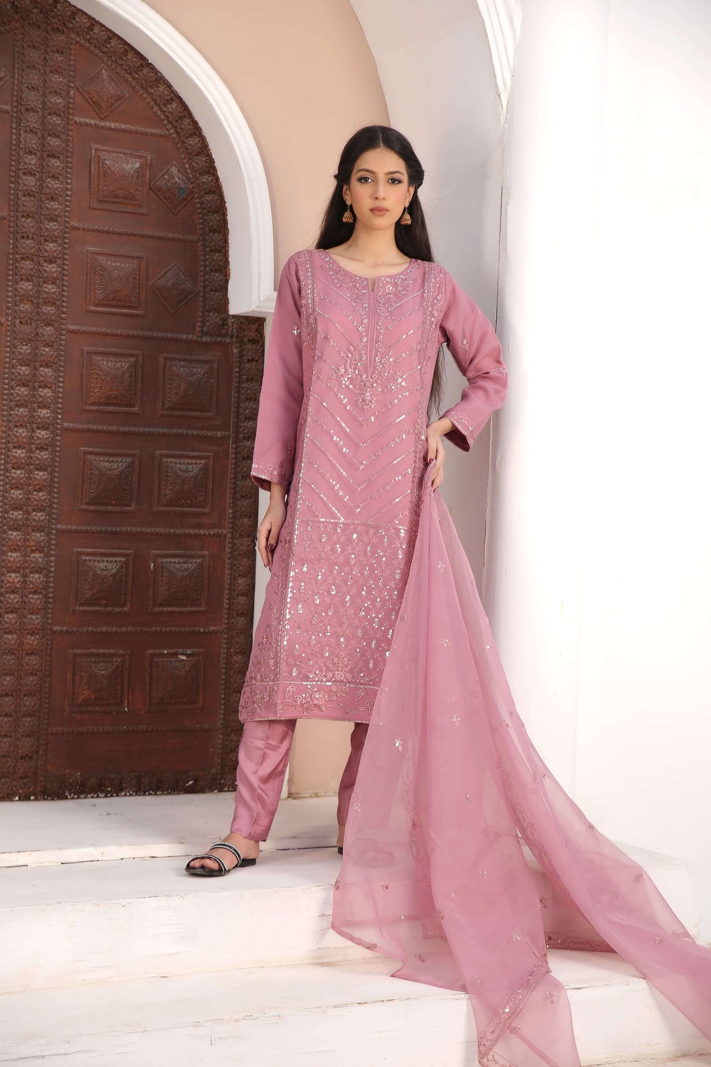 Woman in a pink traditional organza fabric shalwar kameez outfit standing 3 pc complete