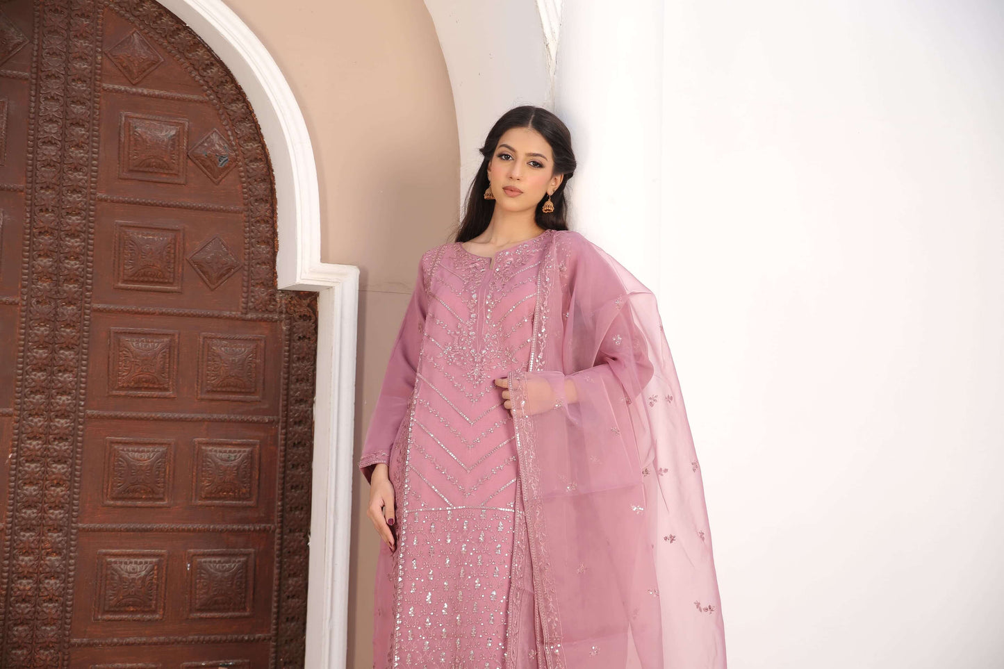 Woman in a pink traditional organza fabric shalwar kameez outfit standing clsoeup