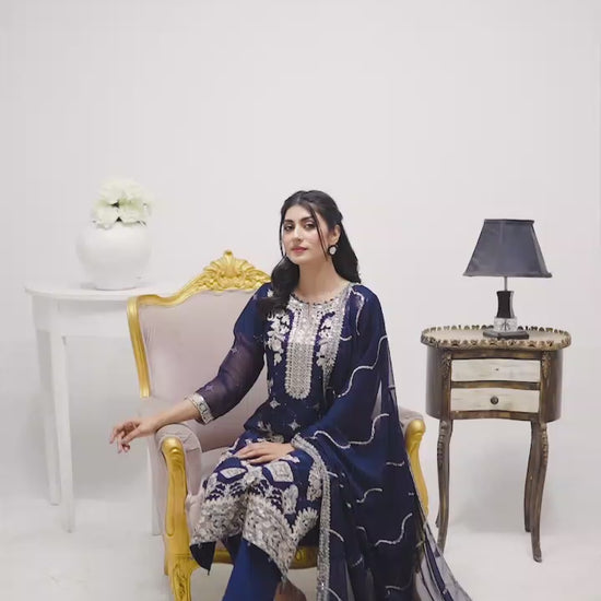 Model wearing navy blue chiffon 3-piece suit with white embroidery, showcasing flowy fabric, embroidery details, and elegant styling in motion.